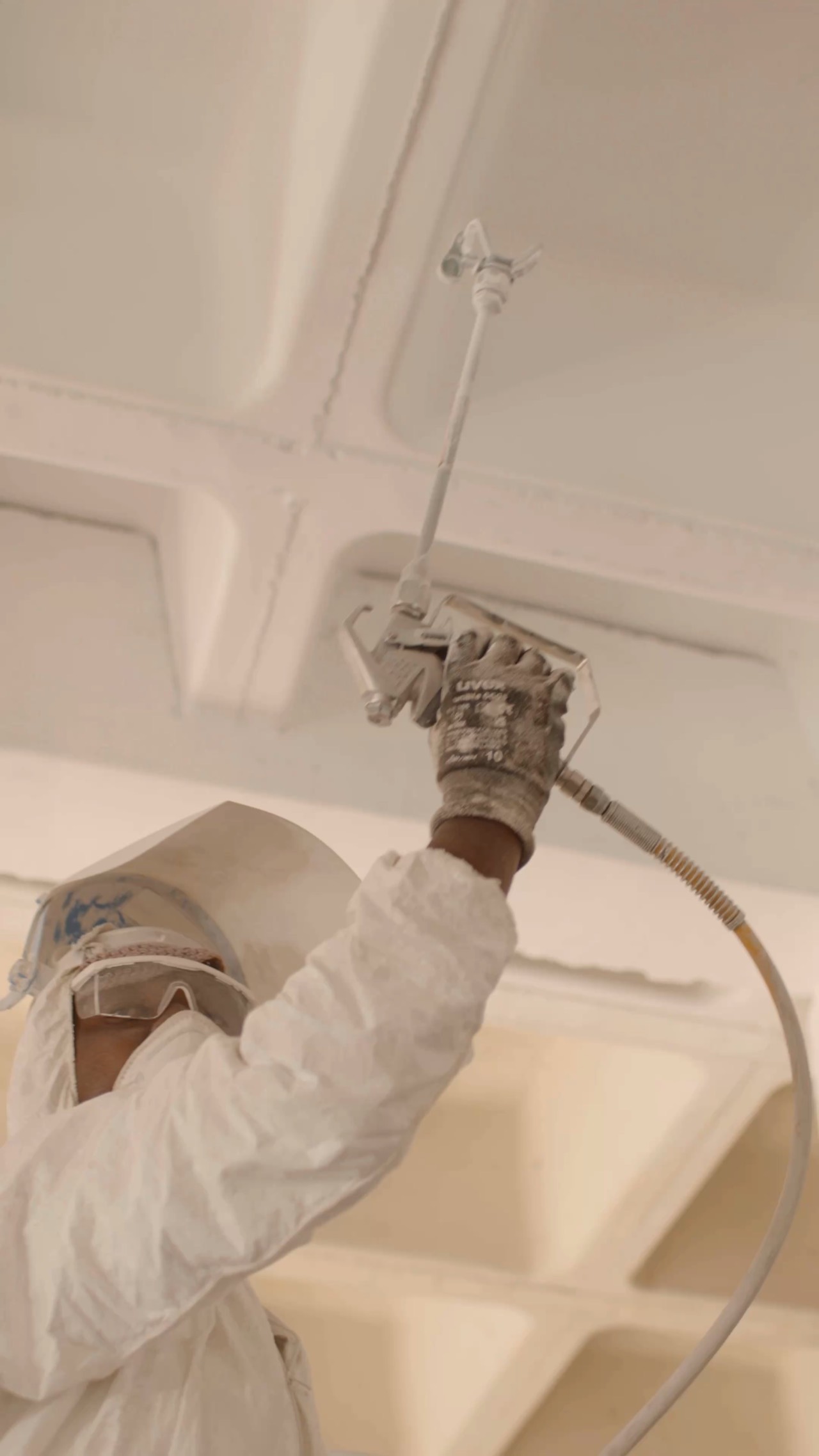 An RB Renovations painter spraying a ceiling white